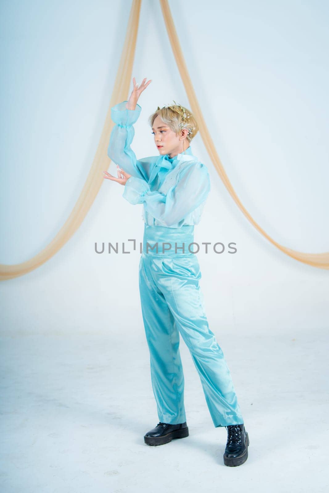 an Asian woman with blonde hair posing with her hands in a white studio