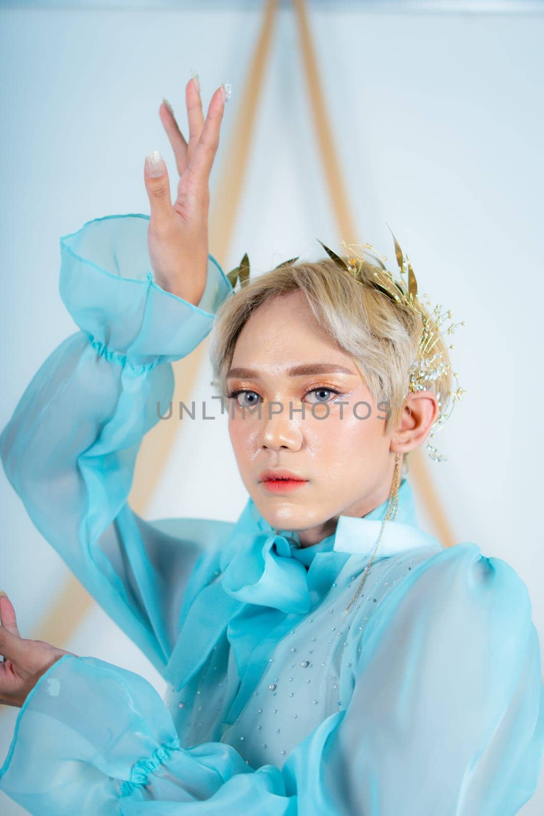 close up photo of an Asian woman with short blonde hair and wearing a blue dress in a white studio
