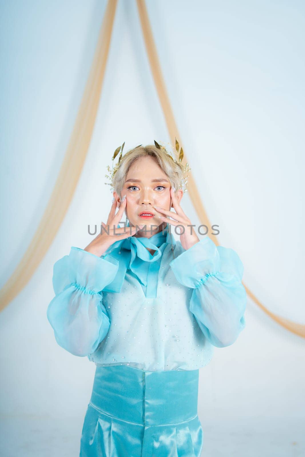 an Asian woman with glowing makeup posing very elegantly in a white room