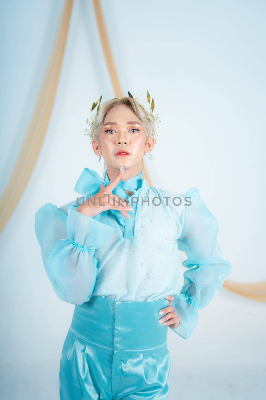 an elegant woman with blonde hair wearing a golden crown and a blue dress in a white room
