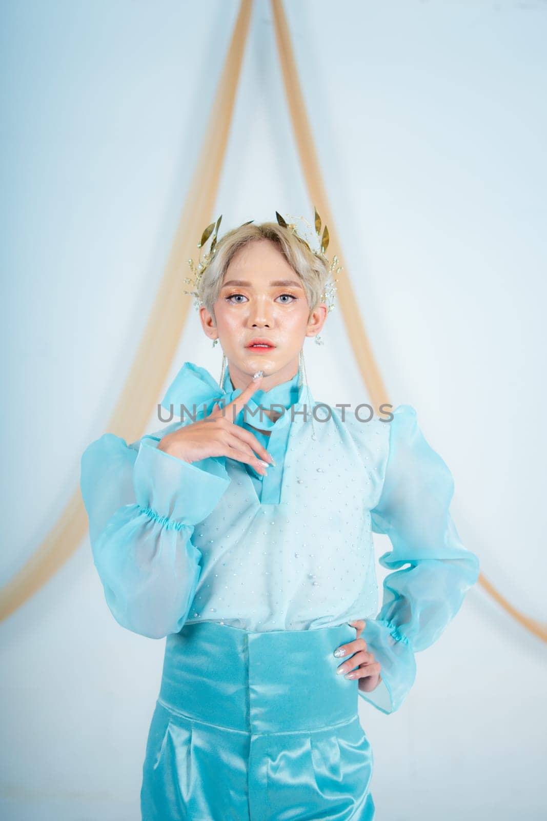 an elegant woman with blonde hair wearing a golden crown and a blue dress in a white room