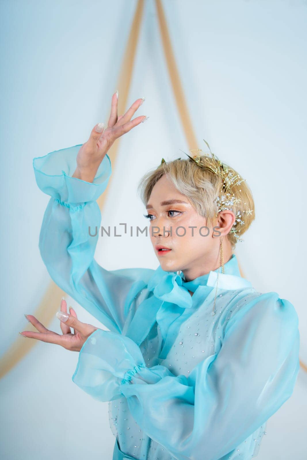 close up photo of an Asian woman with short blonde hair and wearing a blue dress in a white studio