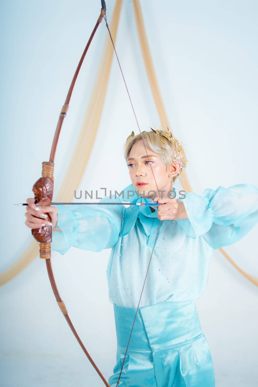 an Asian woman with blonde hair holding an arrow while wearing a blue dress in a white room