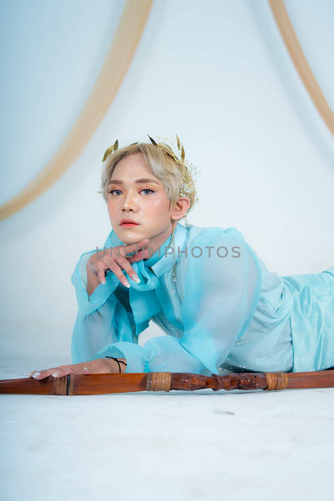 a princess in a blue dress posing on the floor with a bow in a white room