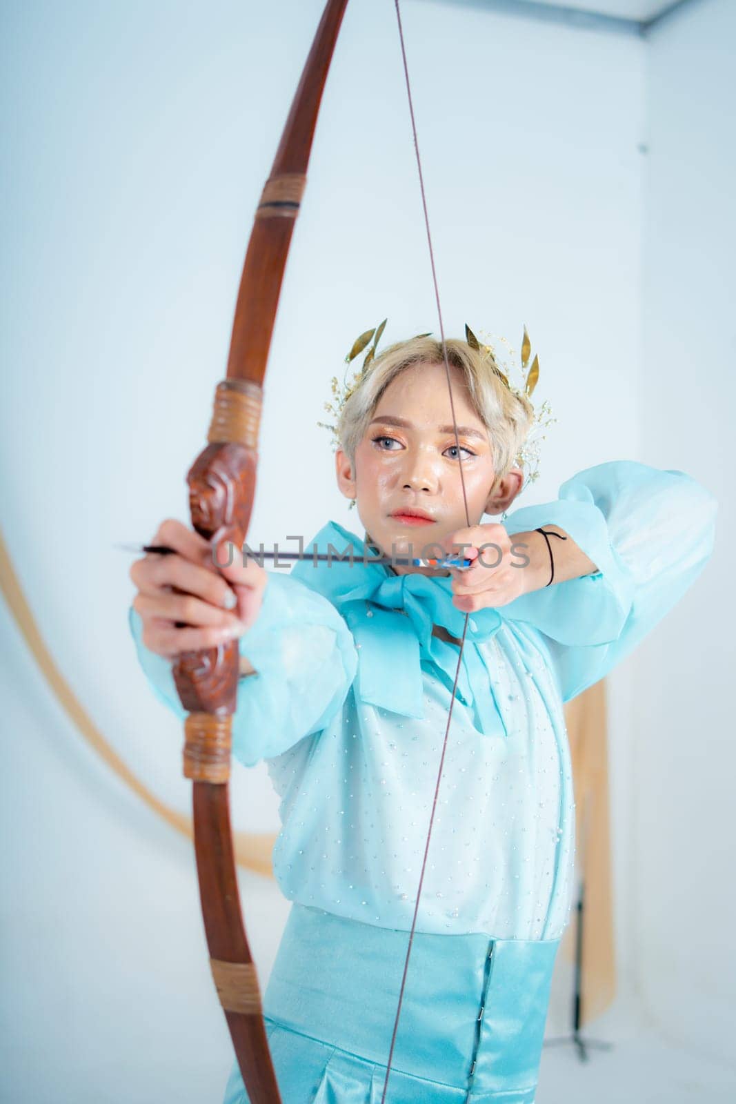 a princess in a blue dress pulling a bow with her hand in a white room