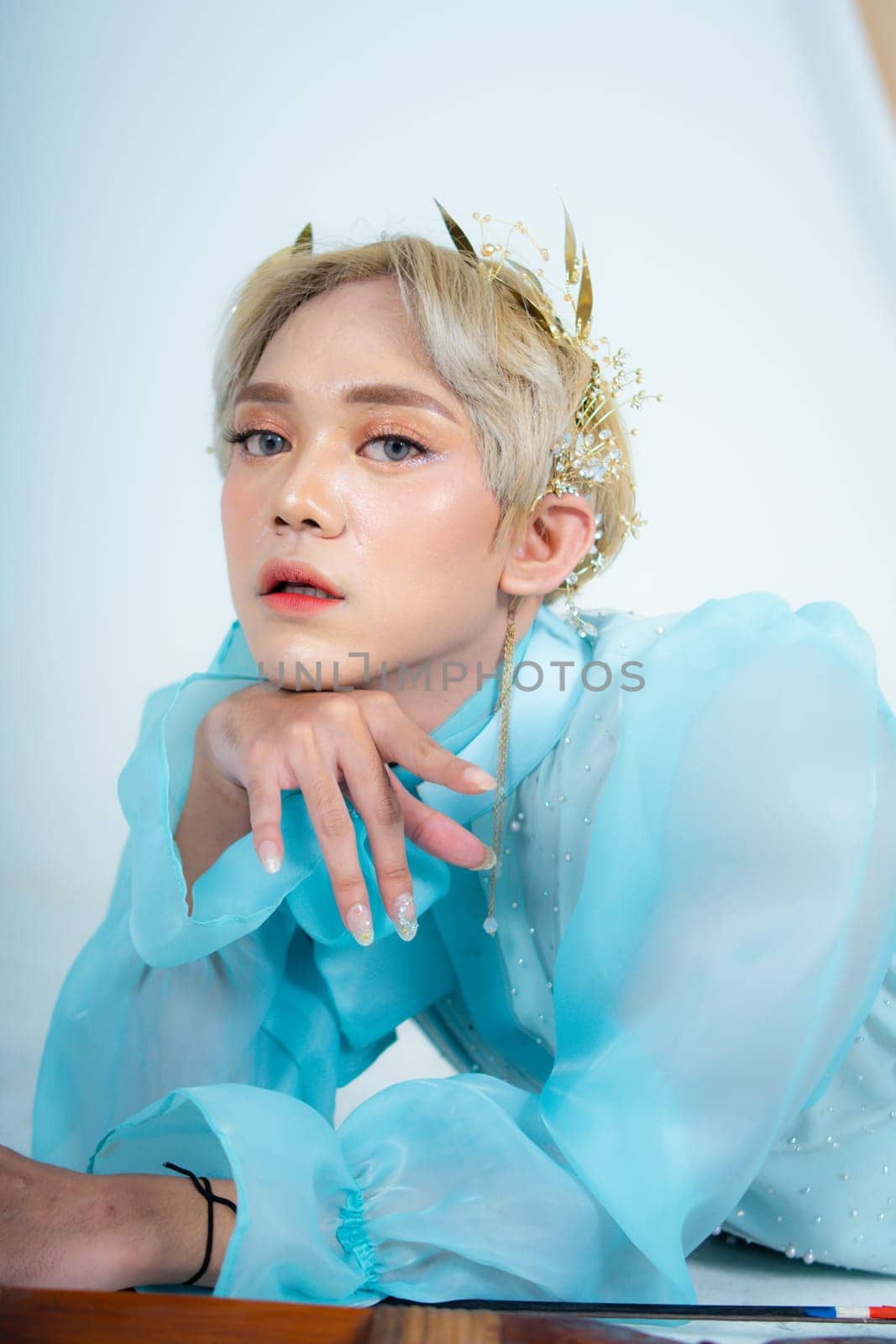 a woman with flawless makeup wearing a golden crown on her blonde hair in a white room