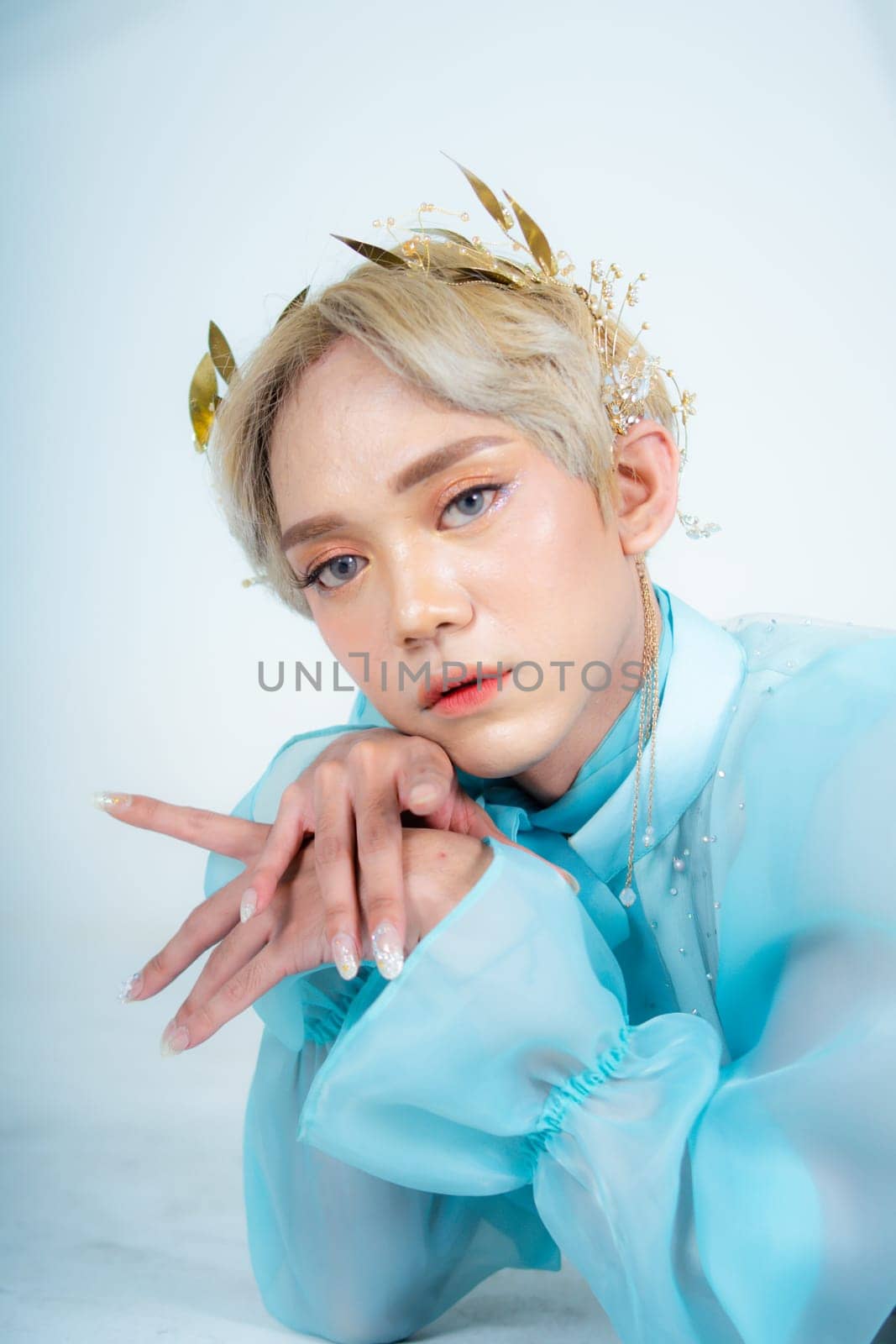 a woman with flawless makeup wearing a golden crown on her blonde hair in a white room