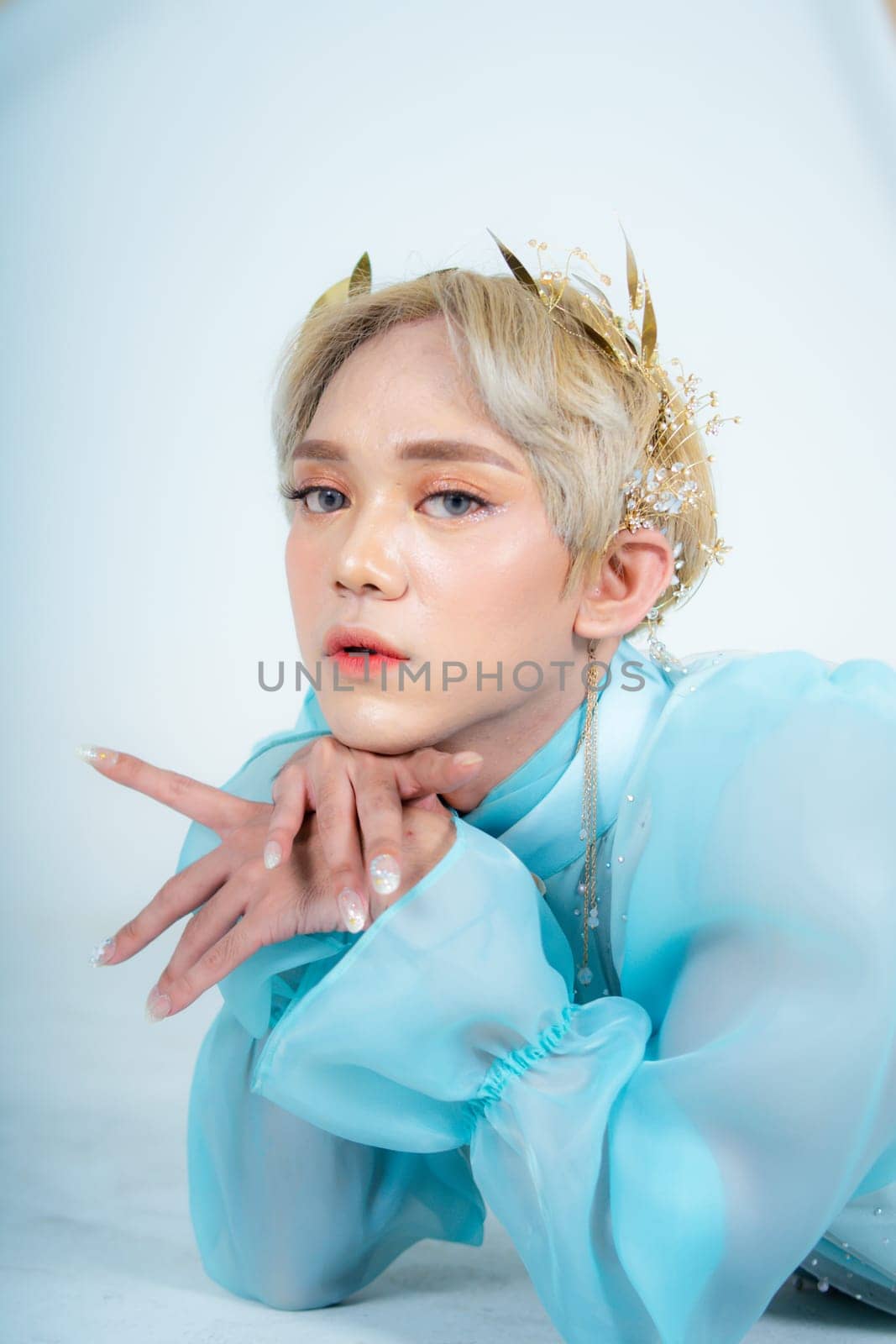 a woman with flawless makeup wearing a golden crown on her blonde hair in a white room