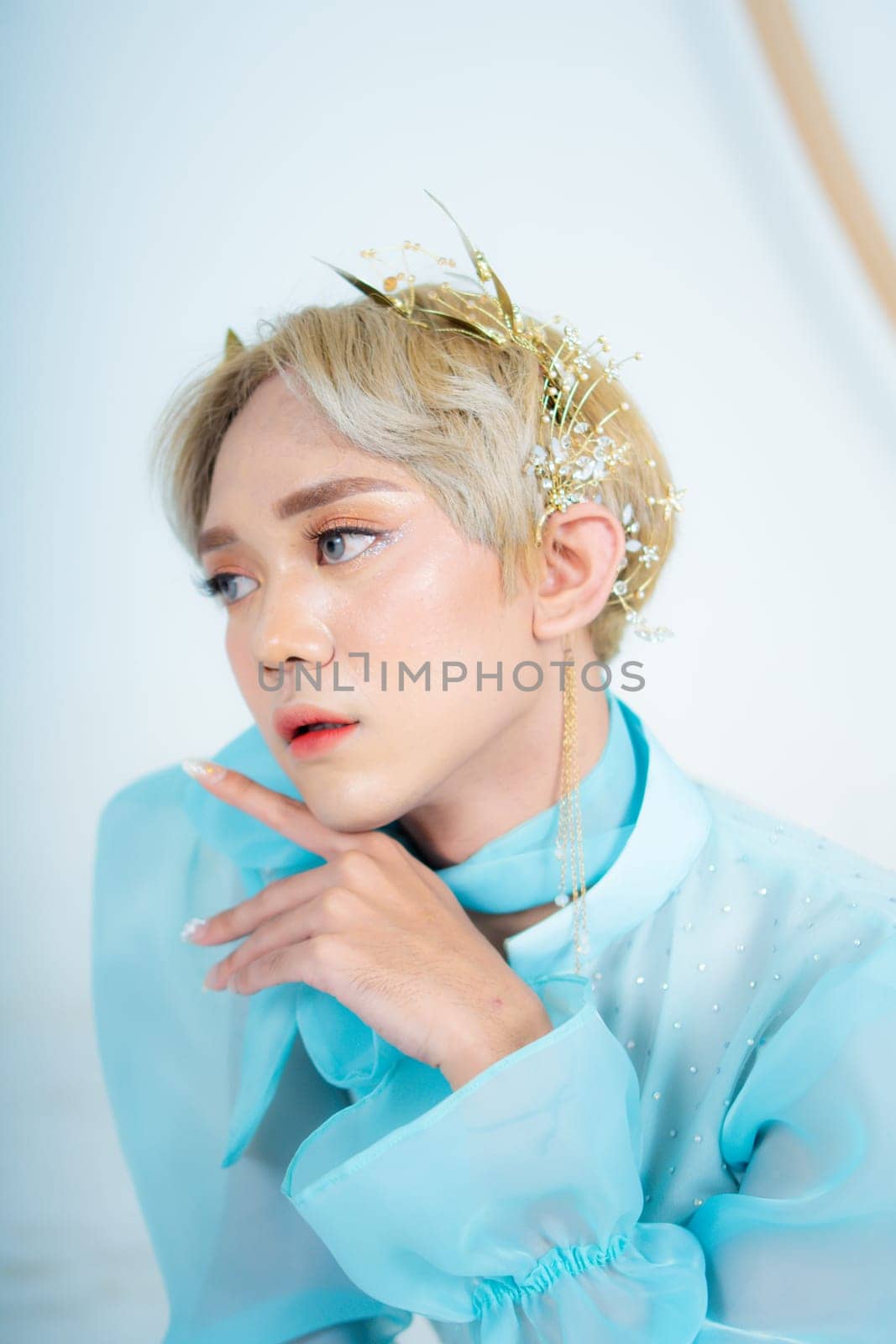 a royal princess posing with a golden crown and blonde hair very cutely in a white room