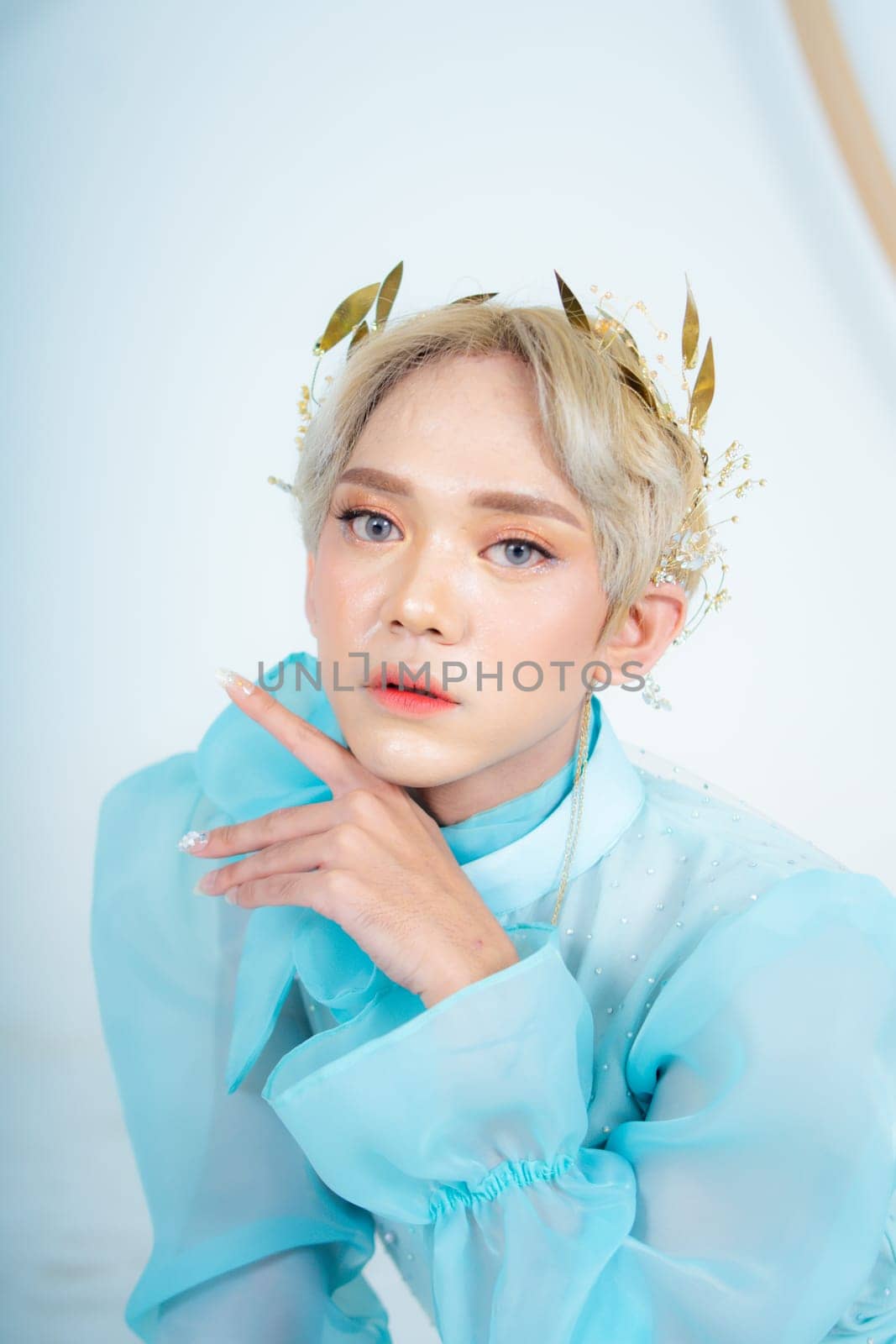 a royal princess posing with a golden crown and blonde hair very cutely in a white room