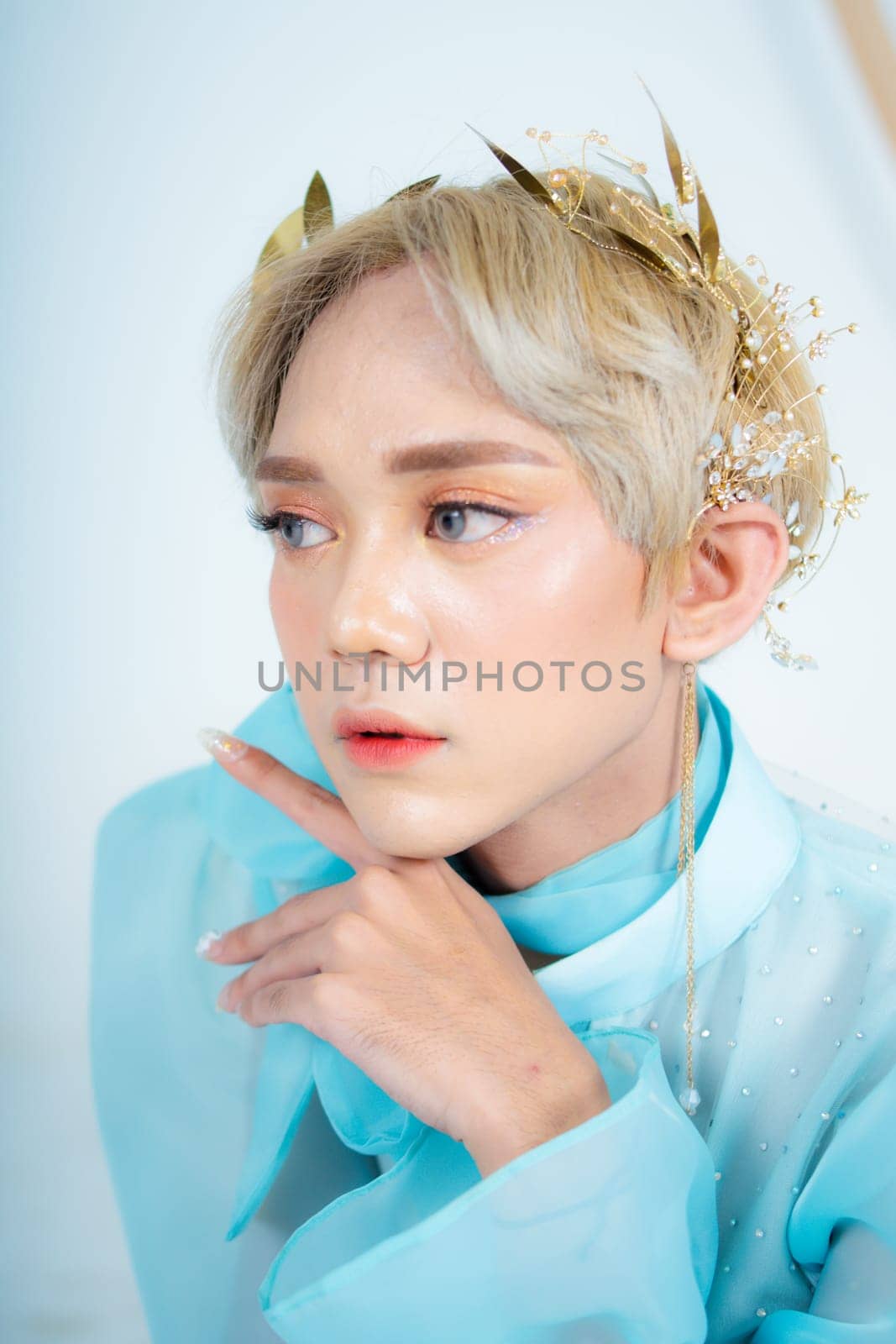 a royal princess posing with a golden crown and blonde hair very cutely in a white room