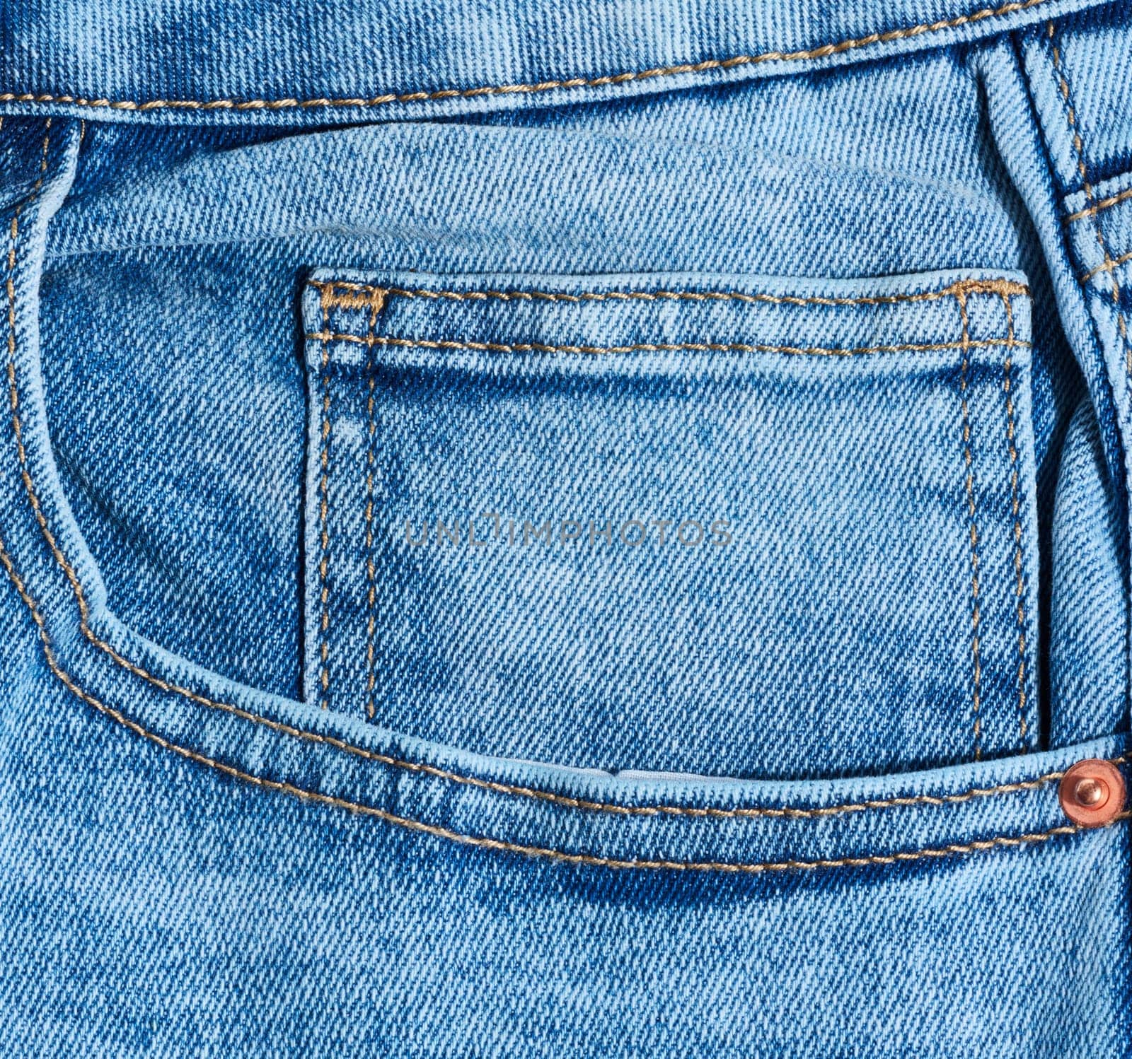 Close up of blue denim jeans showing a front pocket corner with distinct orange stitching detail