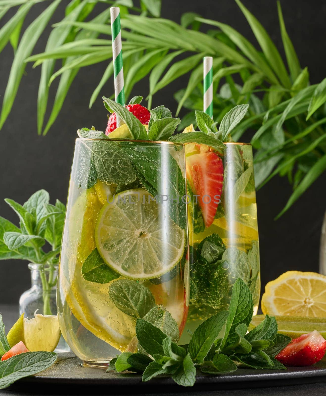 A refreshing drink in a glass with lemon slices, strawberries, fresh mint leaves, and sparkling water