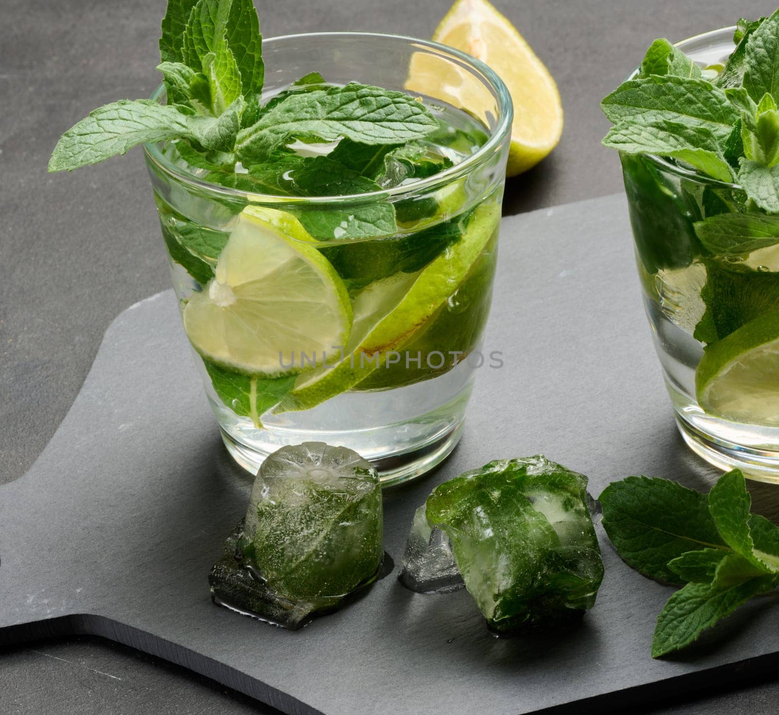 Refreshing mojito cocktail with lime, mint, and ice on dark background