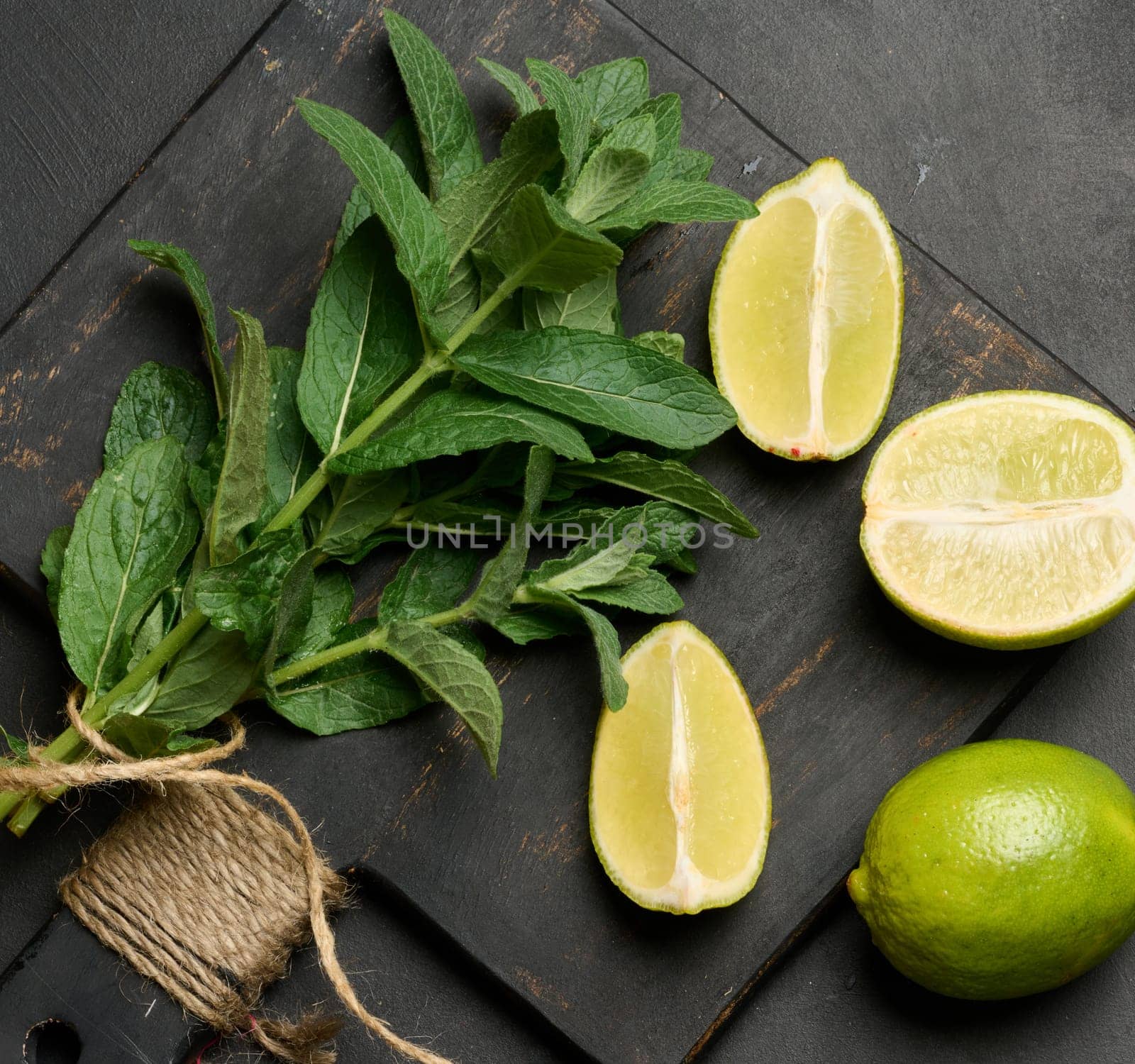 Bunch of fresh green mint on wooden board and lime wedges, top view. Cocktail ingredient
