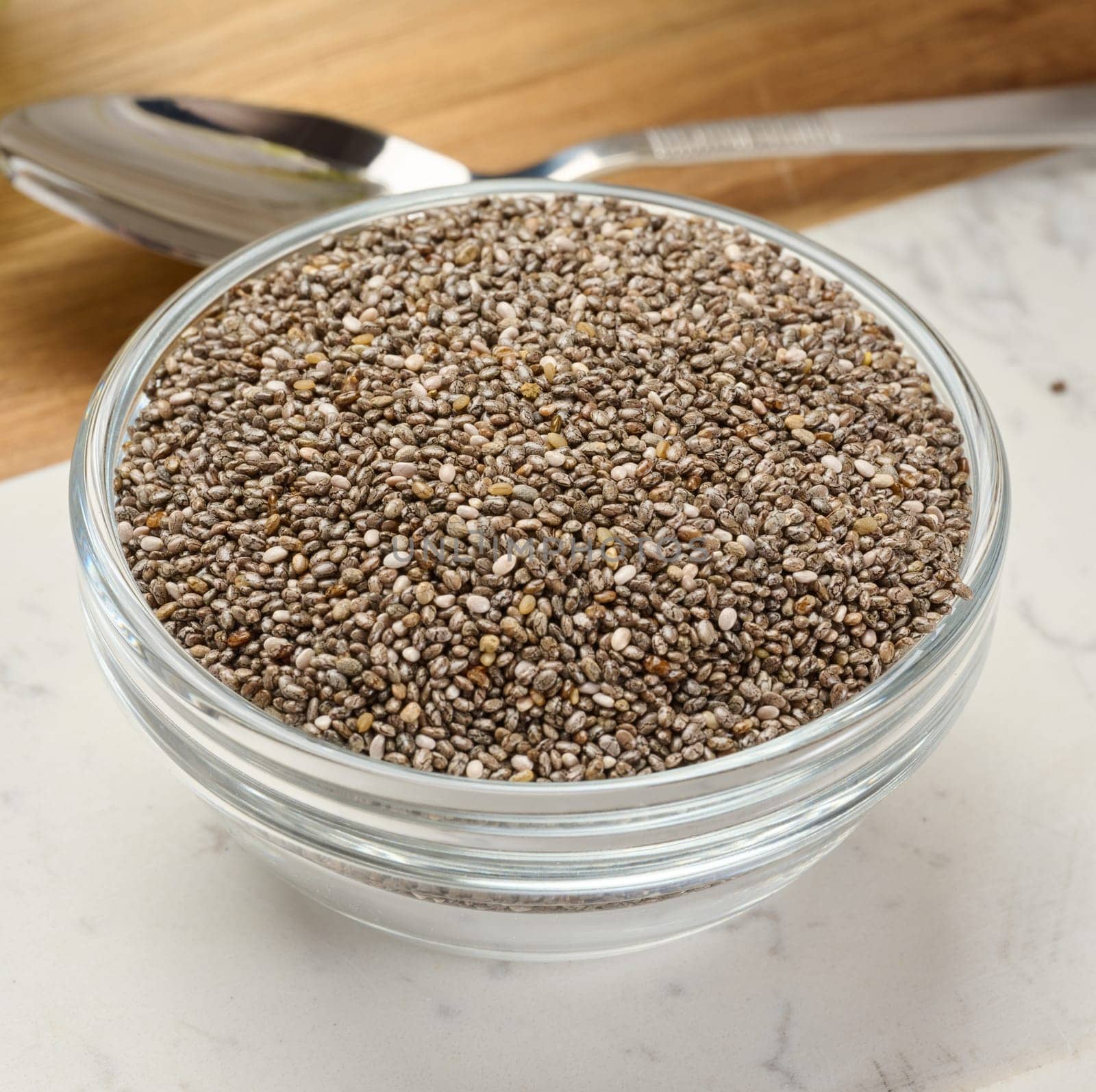 Clear glass bowl filled with dry chia seeds, top view