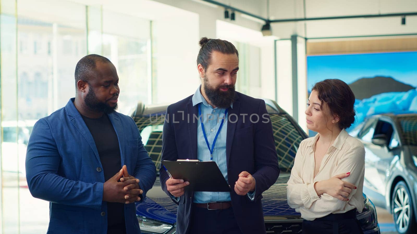Dealership salesman answering customers questions about cars, financing and purchase process. Vehicle showroom agent explaining clients warranties, services and available extra features, camera A