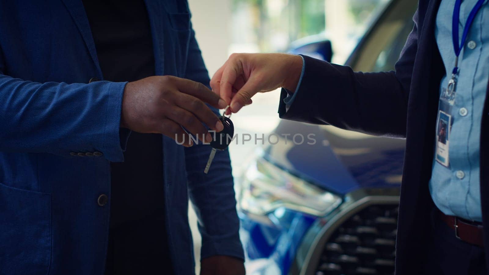 Showroom dealer signing forms for customers after finishing deal, shaking hands. Dealership agent completes documentation for vehicle sale, giving car keys, camera A close up