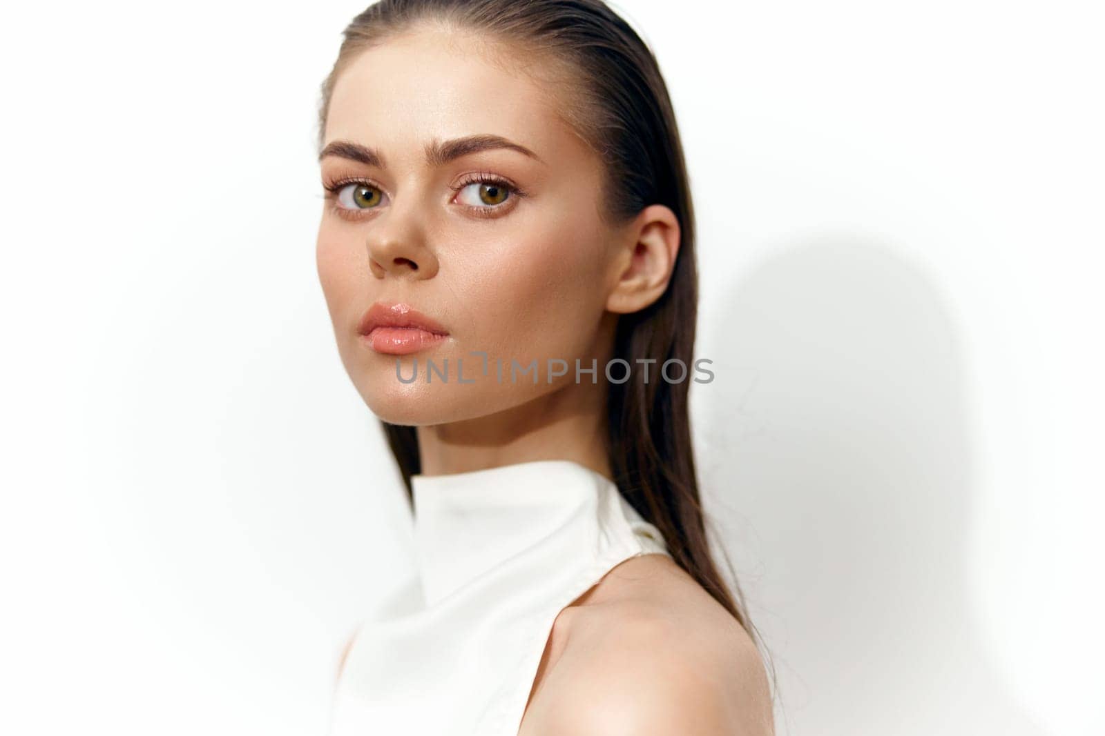 Stunning female model exuding elegance and calmness, dressed in a minimalistic top with a graceful pose. Soft white background enhances her natural beauty.