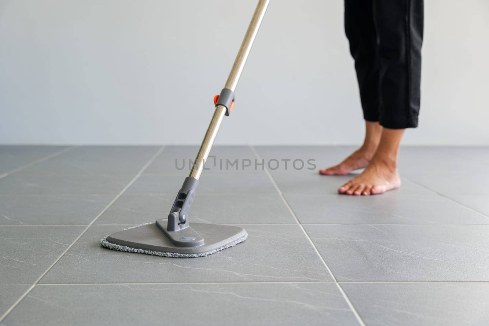 Woman mops the indoor floor, cleaning the front area of her home with a mop and rag. Housewife dedicated to maintaining cleanliness. Represents professional housekeeping and house maintenance concepts