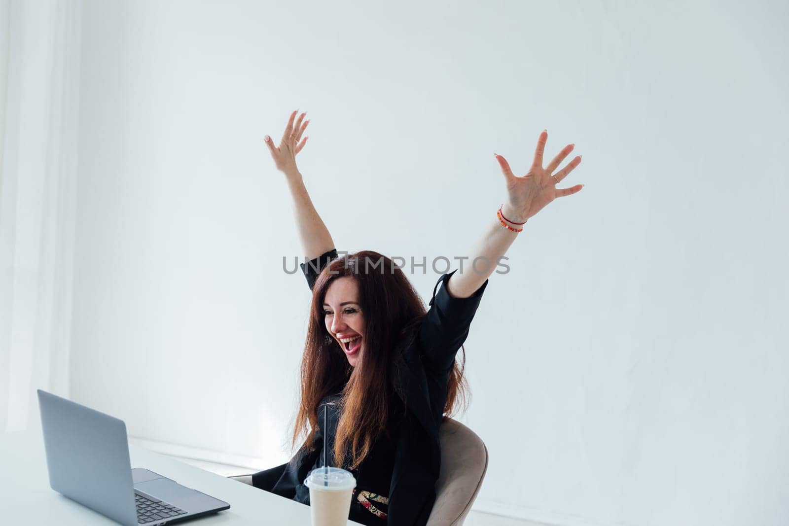brunette woman working on a table with a laptop shouting happily laughing