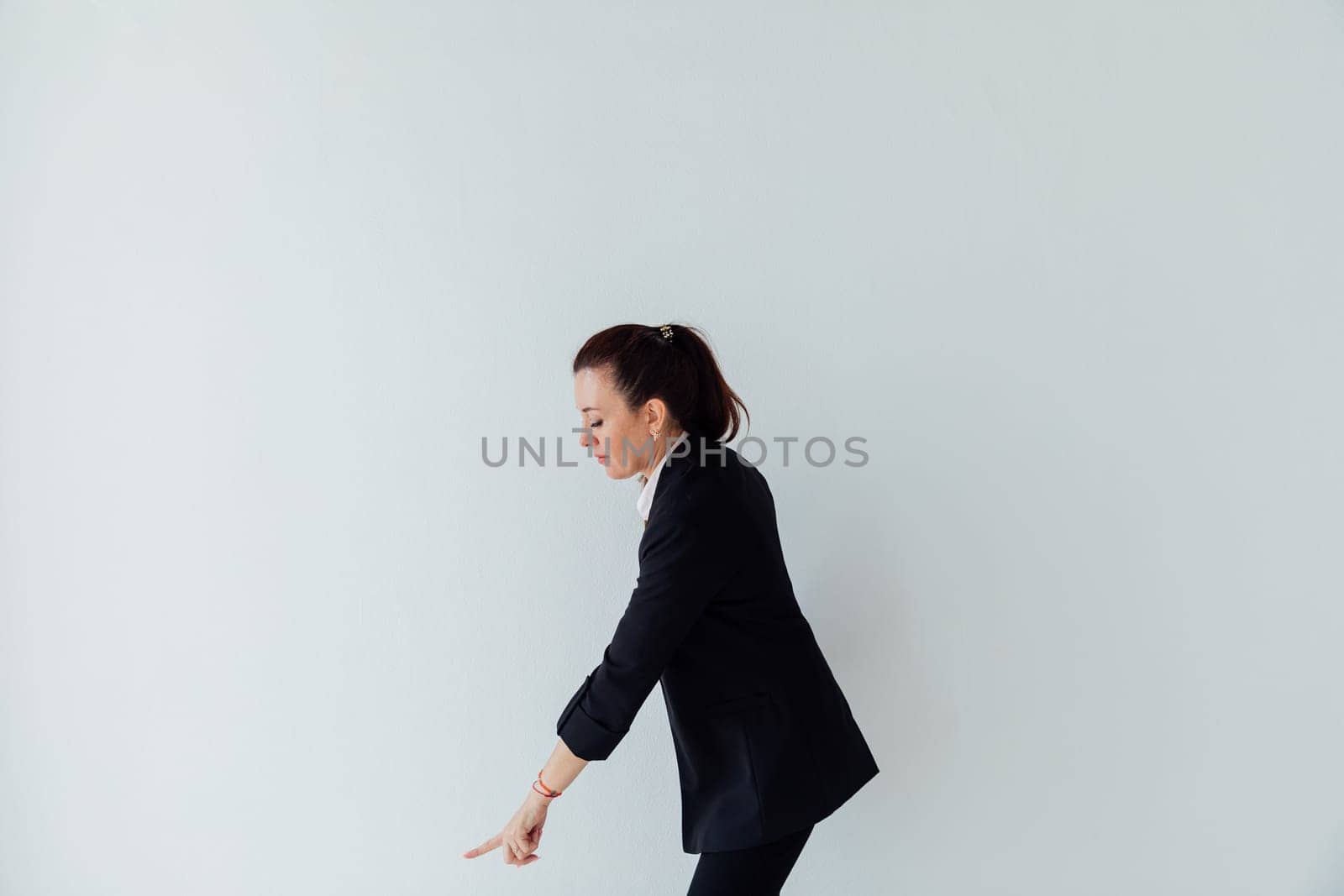 Brunette woman in business suit showing direction with her hand on white background
