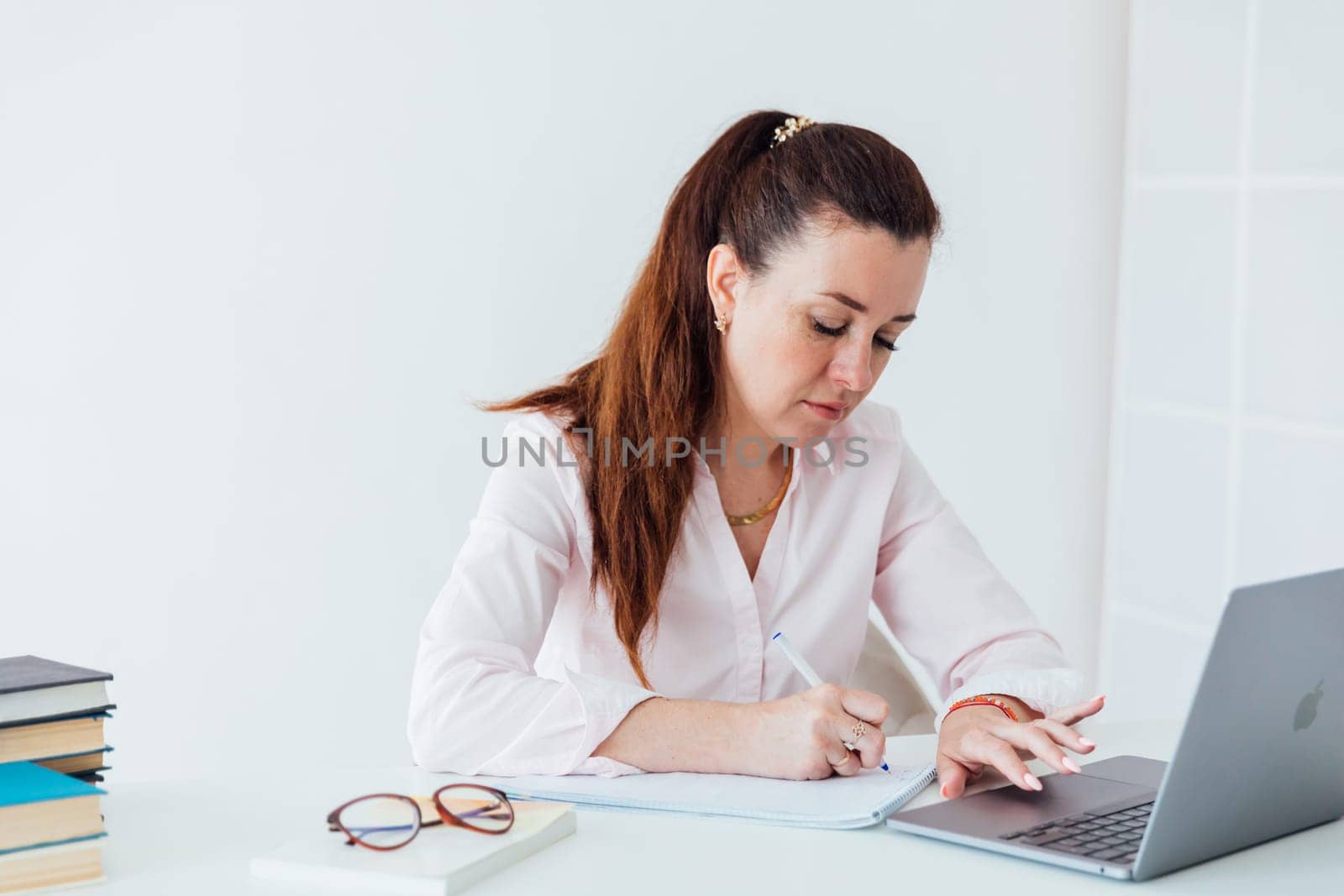 Brunette woman working at office desk with laptop online
