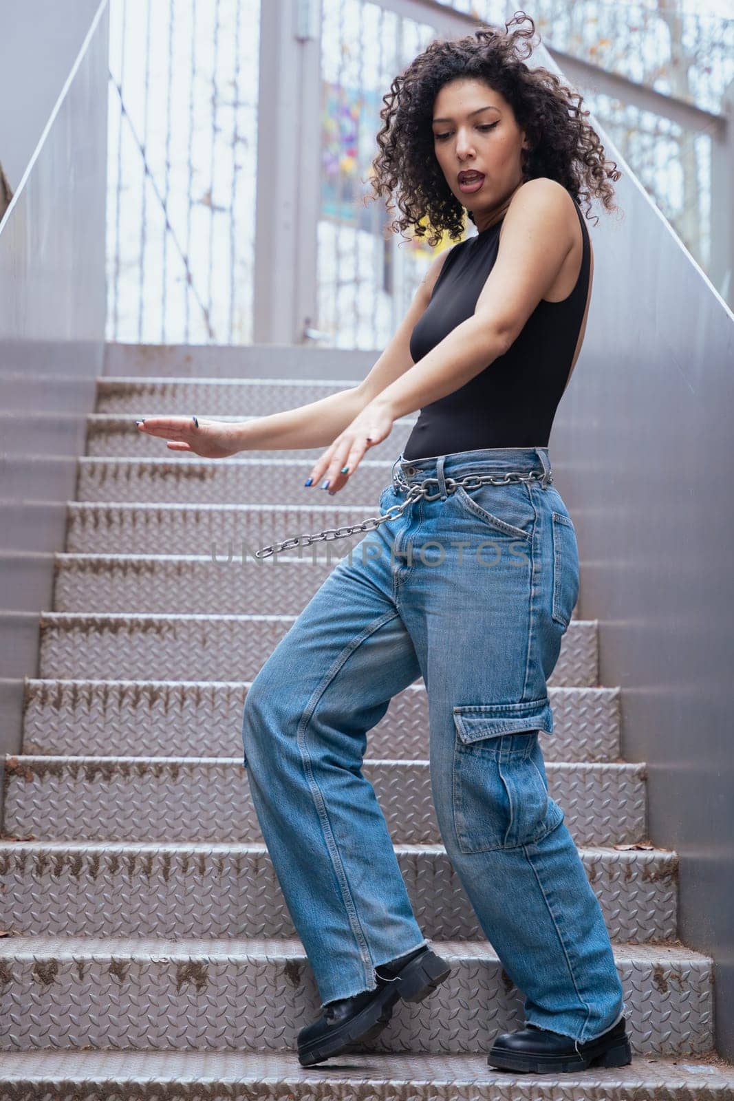 African American woman dancing in a creative pose between benches in an urban setting. he wears casual clothes and shows balance,strength, and expression. Concept of movement, art,and freedom.Vertical