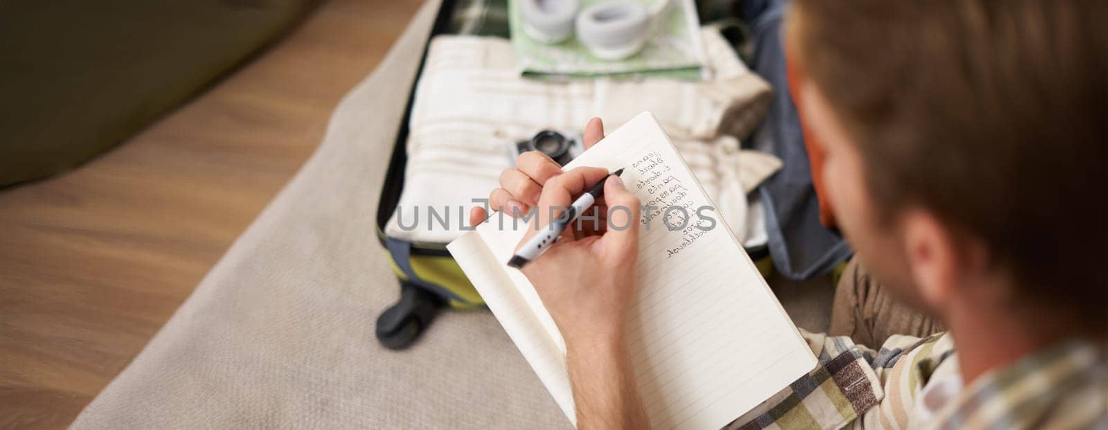 Close up portrait of man going through check-list, packing for holiday, looking at items he wants to bring on vacation.