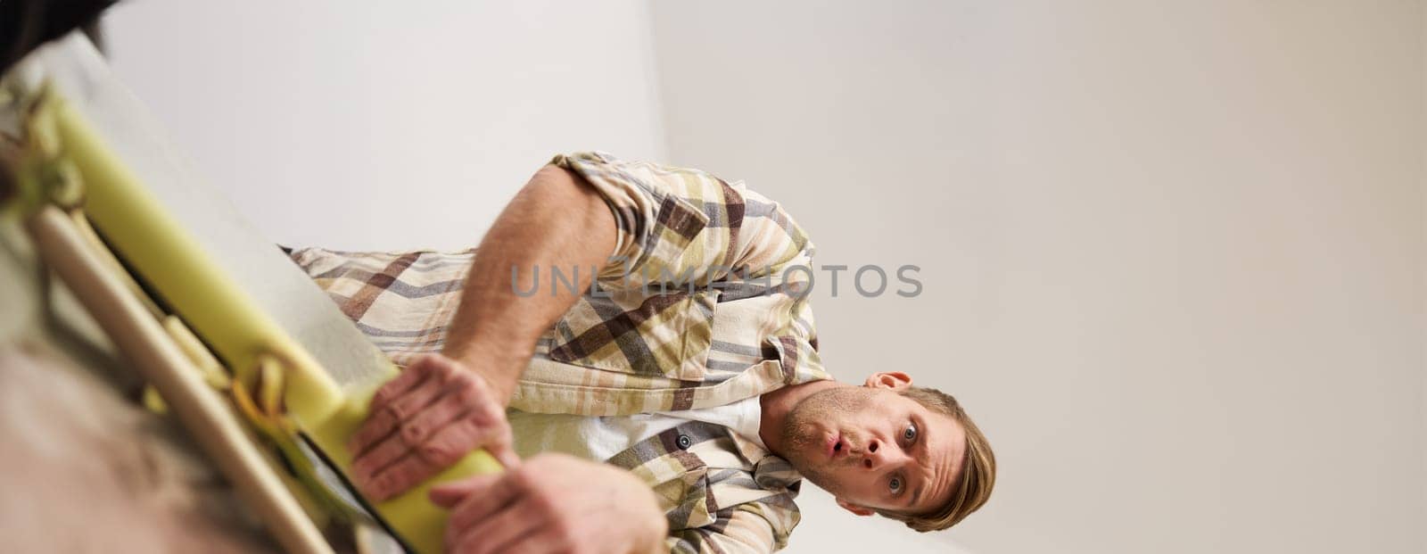 Vertical shot of man trying to press suitcase and close zipper, packing clothes for vacation. Tourist going on holiday, preparing for travelling abroad. Tourism concept