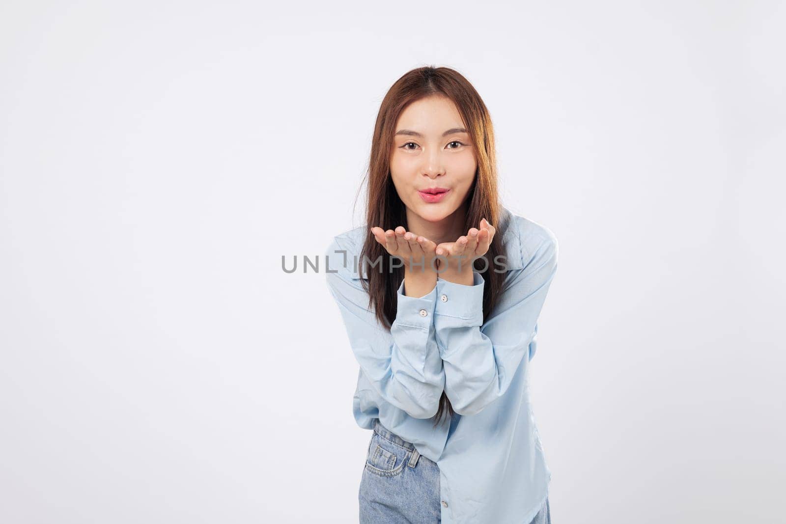 Woman blowing air kiss with both palms extended, happy woman shows affection with bright expression and loving gesture isolated on clean white studio background.