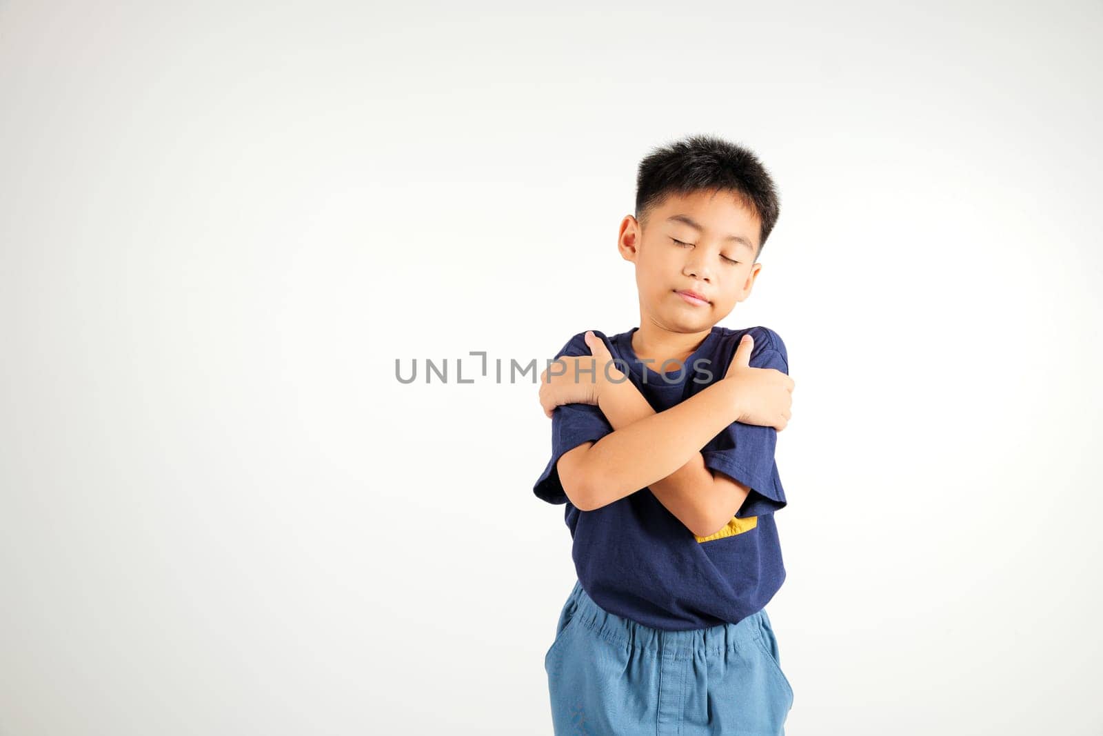 Happy young child smiling Asian boy hugging herself remember a moment studio short isolated on white background, Self care and self esteem concept, Lifestyle primary kid love yourself carefree
