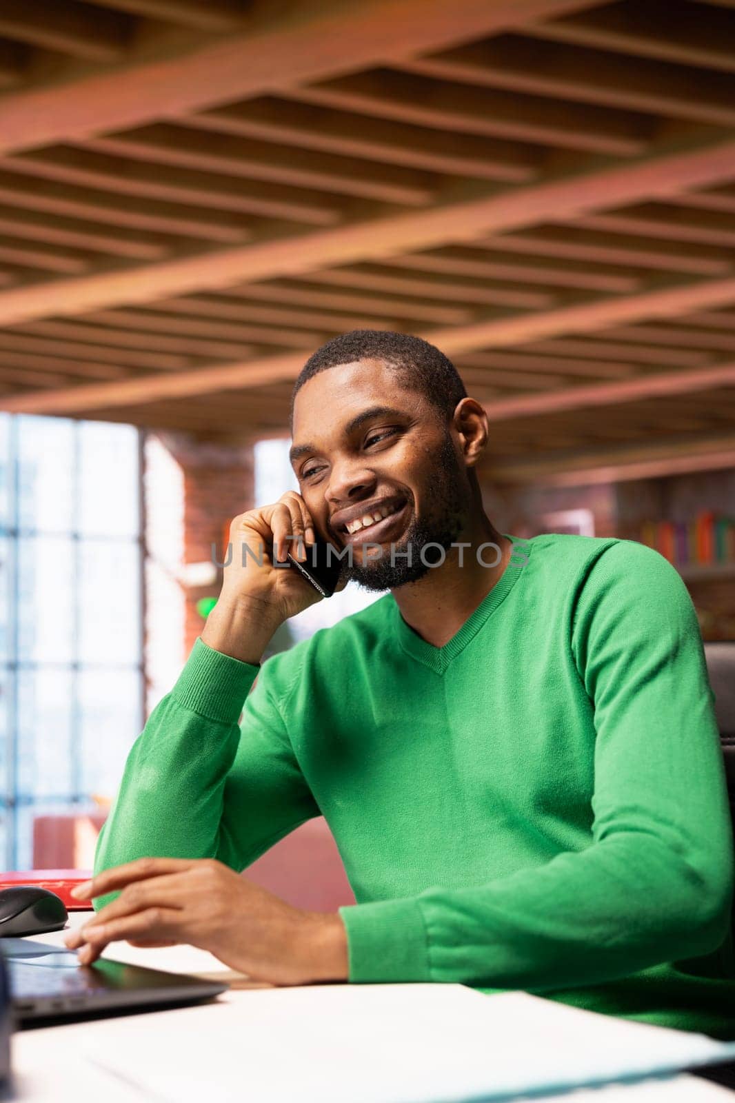 Smiling man at home having friendly conversation with friend over phone call on smartphone. African american person having fun catching up with mate in telephone call, having lively discussion