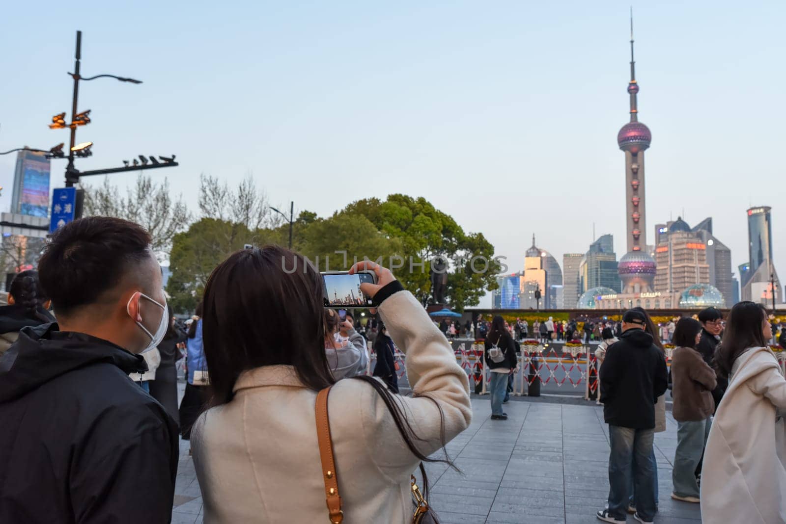 Shanghai, China – 1 April 2025: Chinese tourists take photos of the Pudong skyline with Oriental Pearl Tower, Jin Mao Tower and Shanghai Tower from Nanjing Road promenade