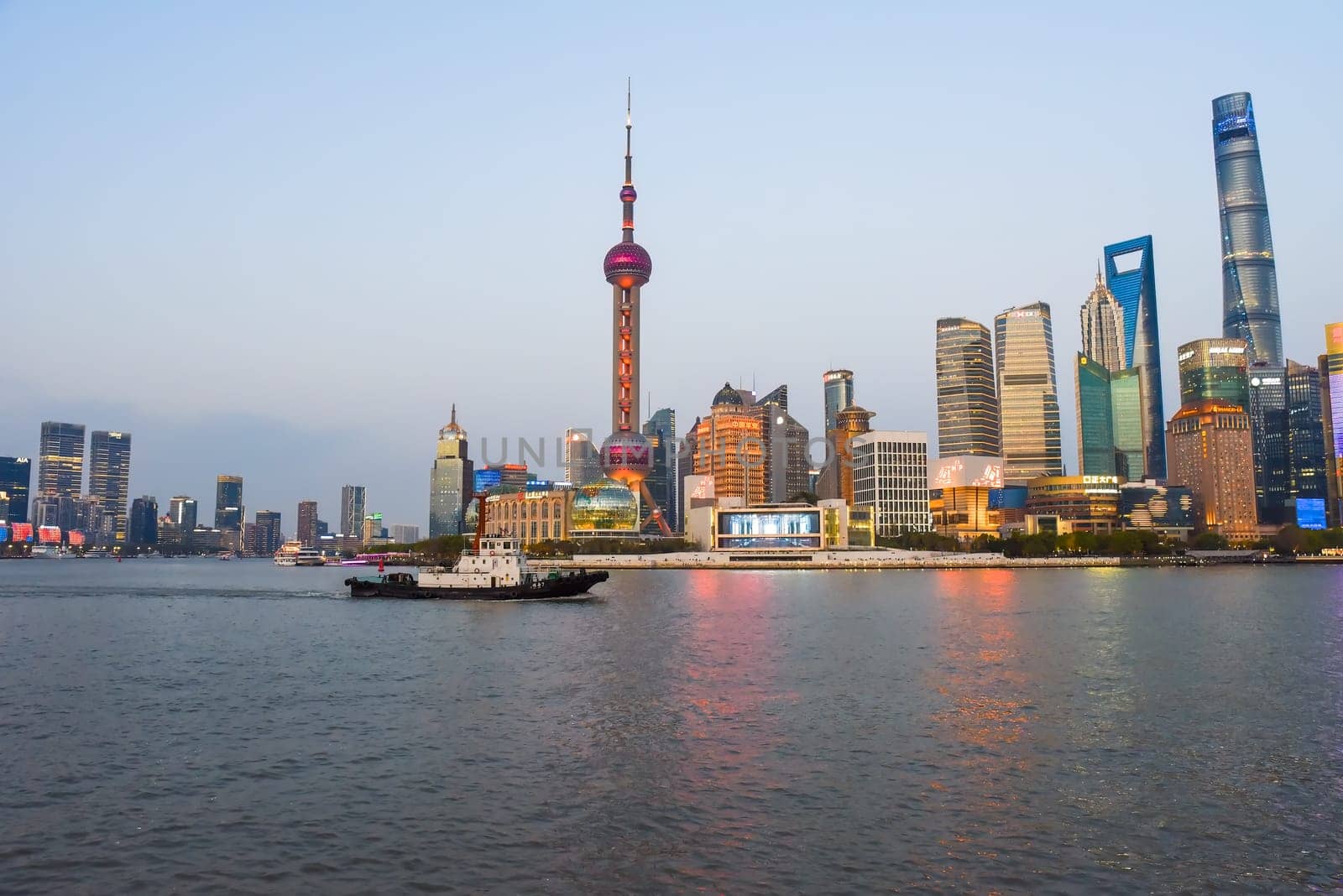 Shanghai, China - 1 April 2025: Tourist boat passes along the Bund waterfront in front of Pudong skyline featuring Oriental Pearl Tower and Shanghai Tower