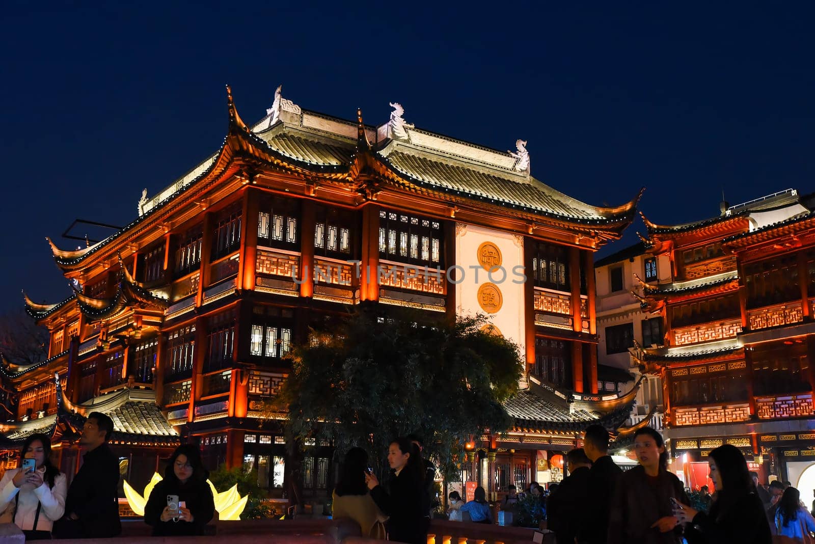 Shanghai, China - 1 April 2025: Yuyuan Old Street illuminated at night, showcasing traditional Chinese architecture and vibrant red lanterns