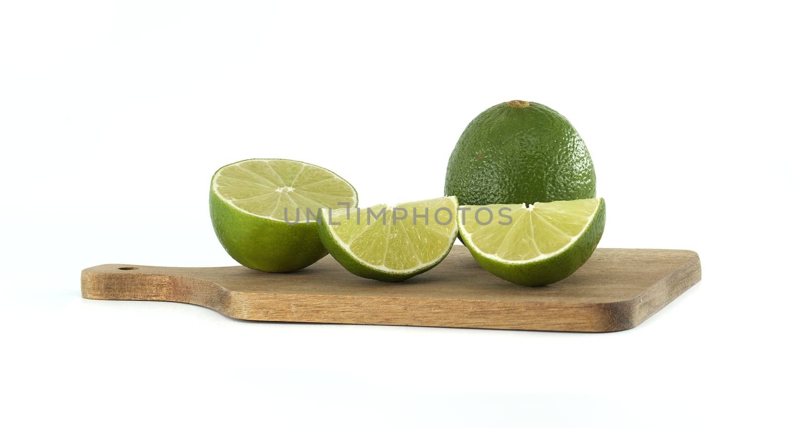 Featuring one whole lime, a halved lime, and two vibrant lime slices, all resting on a small wooden cutting board against a clean white background