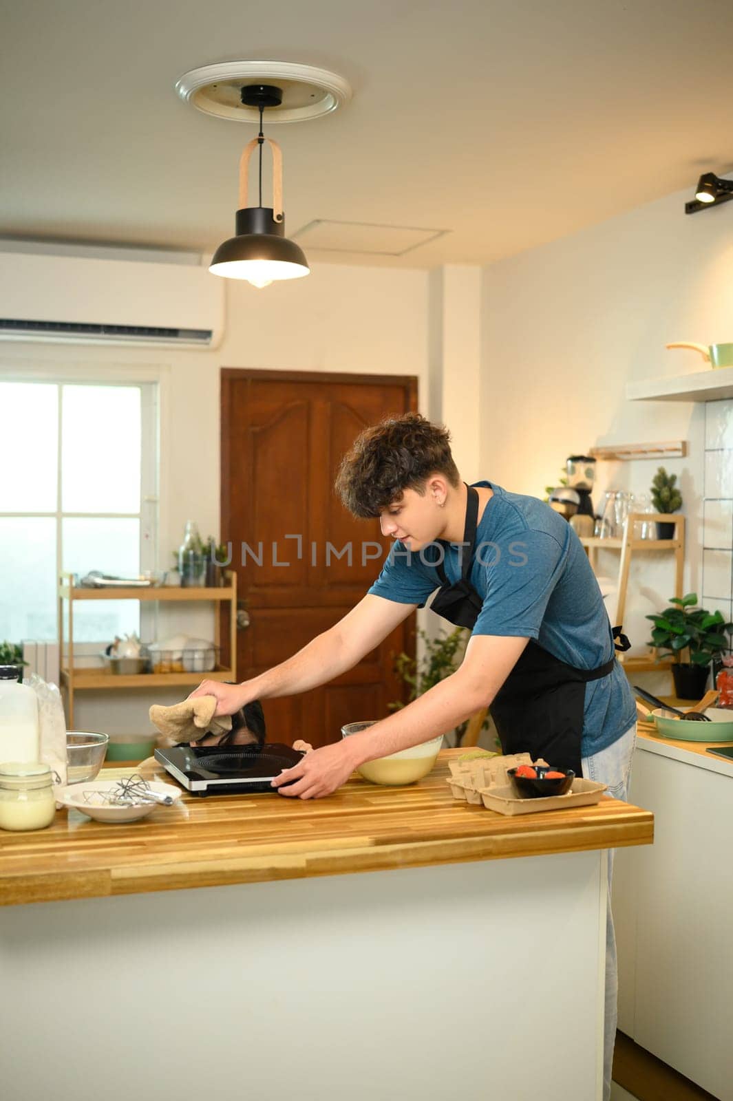 Man using electric griddle to make pancakes in cozy kitchen.