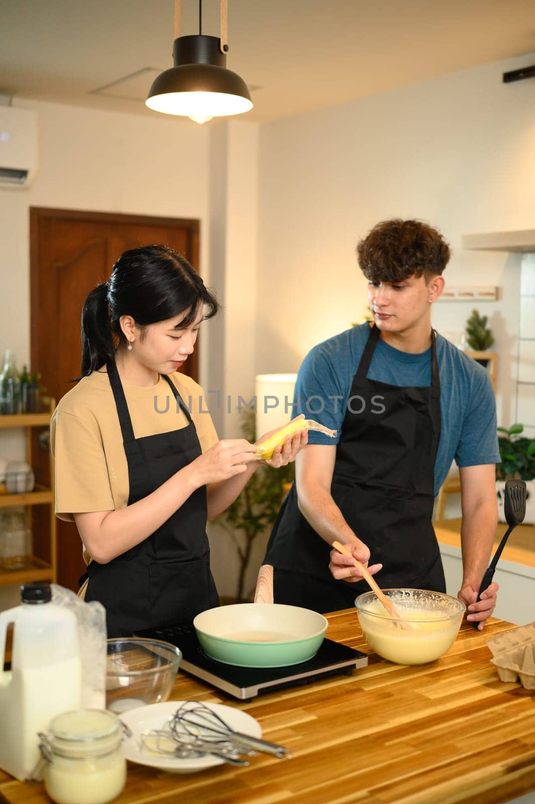 Young couple preparing pancake batter together in a cozy kitchen.