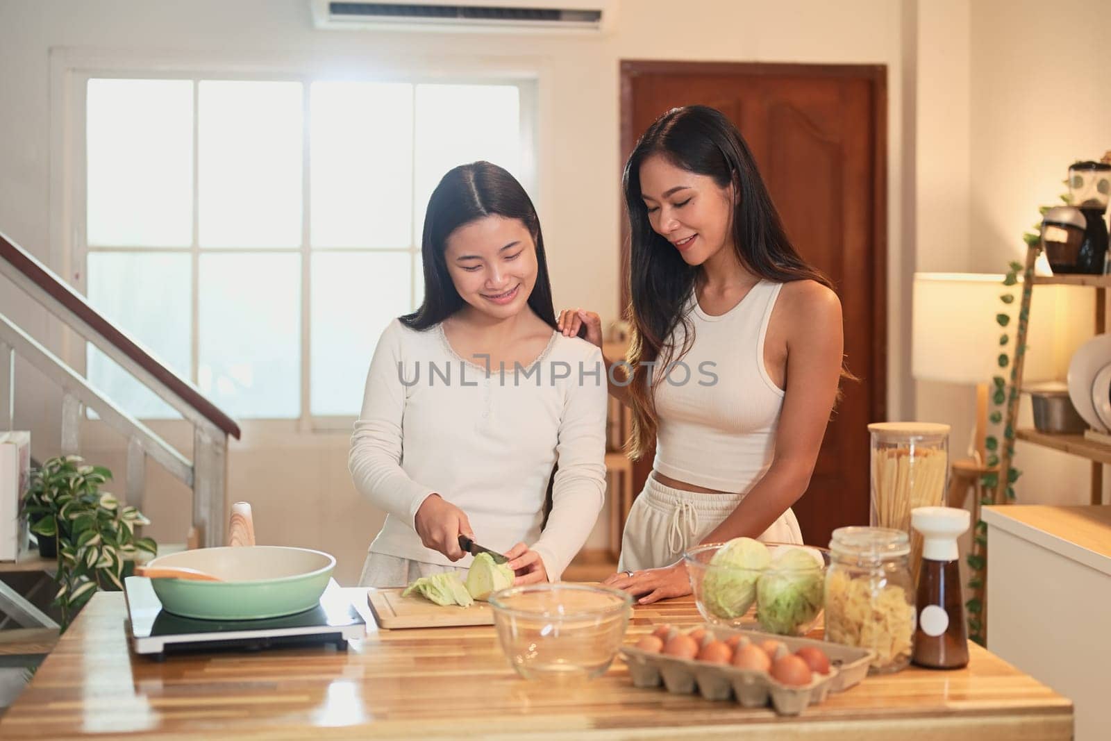 Smiling mother and daughter preparing a healthy meal together in a cozy kitchen at home.