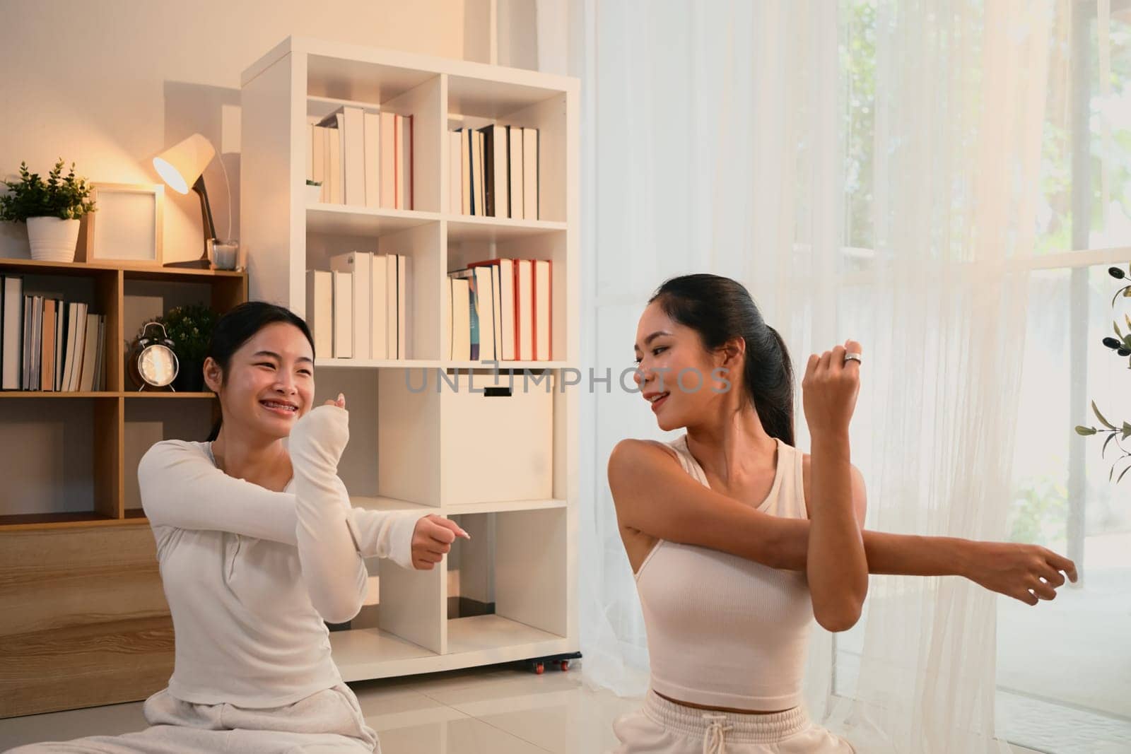 Mother and daughter enjoying a workout session together in a bright, cozy home.