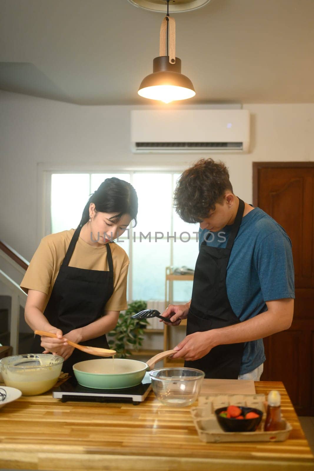 Young couple preparing pancake batter together in a cozy kitchen.