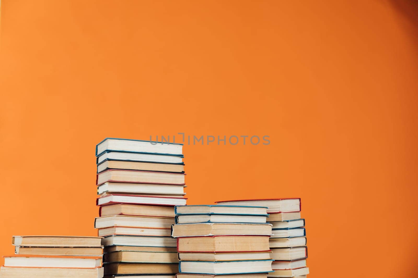 Stacks of old educational books for learning on an orange background