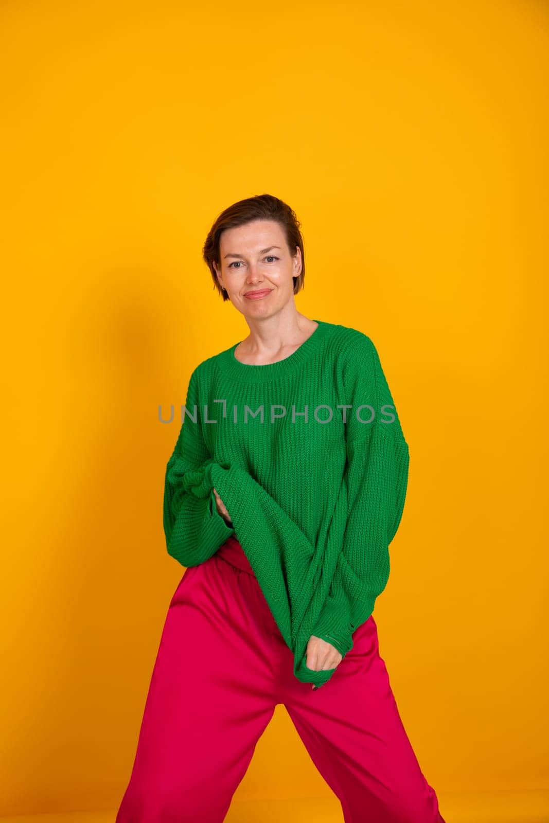 40-year-old woman in green knitted sweater on yellow background