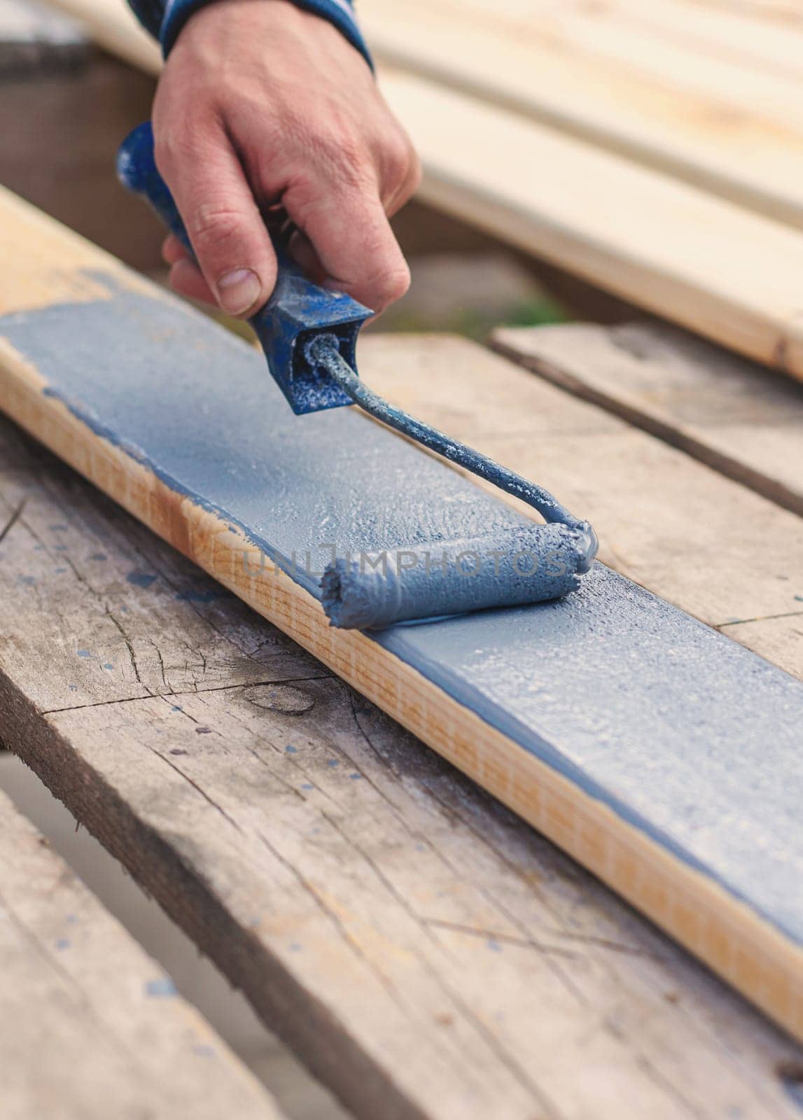 A man paints a board with paint. Selective focus. People.