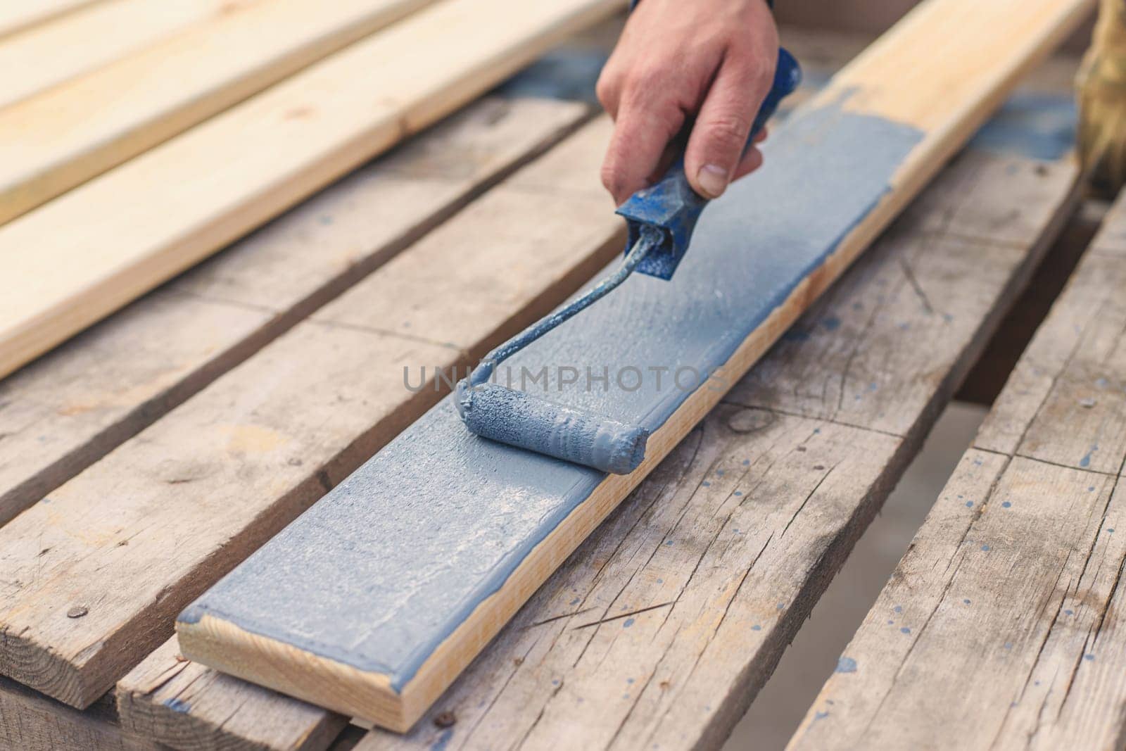 A man paints a board with paint. Selective focus. People.