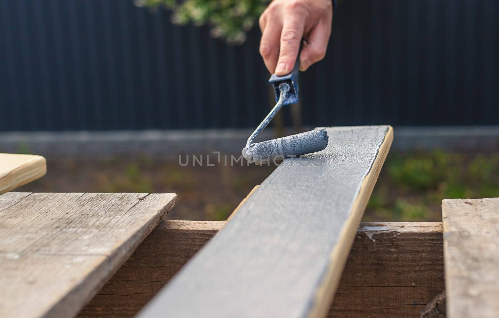 A man paints a board with paint. Selective focus. People.