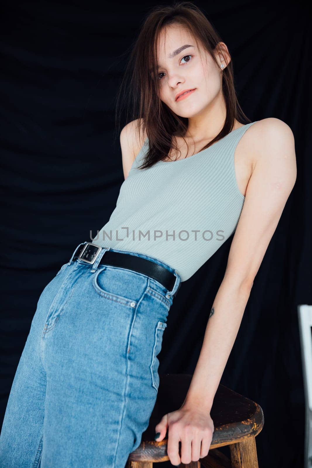 Slim fashion woman in jeans and gray t-shirt on black background