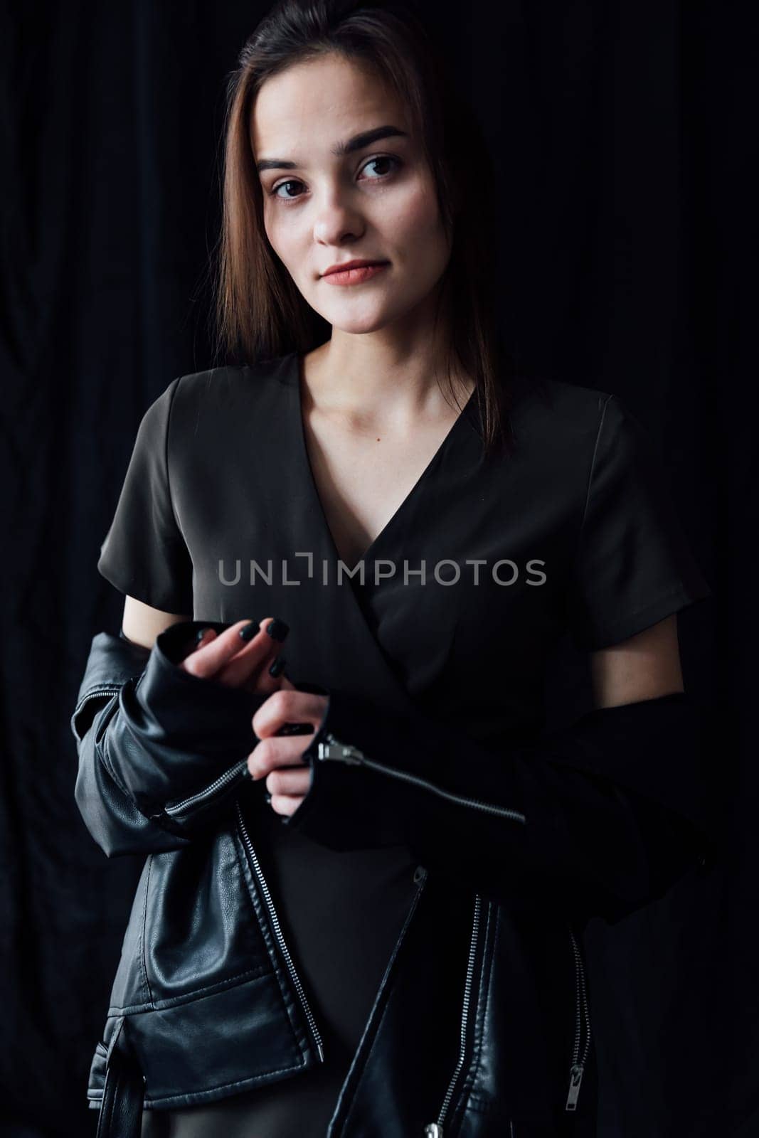 Portrait of Beautiful Fashion Brunette Woman in Gray Dress and Leather Jacket on Black Background