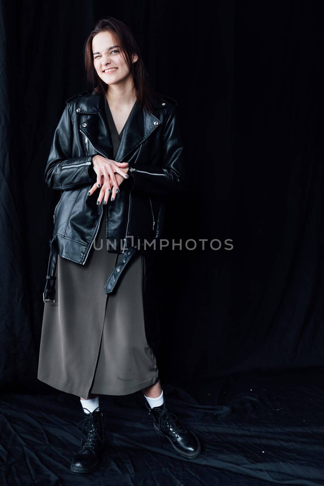 Portrait of Beautiful Fashion Brunette Woman in Gray Dress and Leather Jacket on Black Background
